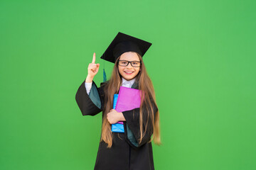 the graduate points her finger at the top and smiles. graduation at school. green isolated background.