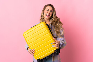 Young Brazilian woman isolated on pink background in vacation with travel suitcase