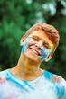 portrait of young happy man dirt in holi paints