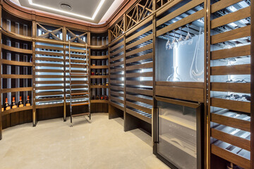 Private wine cellar with shelves on the rack, stepladder. Refrigerator and tasting glasses.