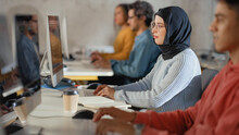 Curious Female Muslim Student Wearing A Hijab, Studying In Modern University With Diverse Multiethnic Classmates. College Scholars Work In College Room, Learning IT, Programming Or Computer Science.
