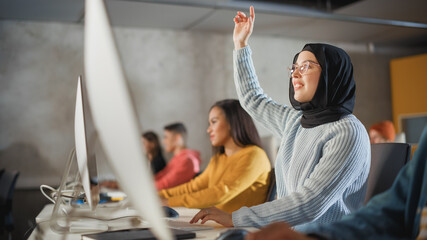 Fototapete - Smart Muslim Female Student in Hijab Studying in University with Diverse Multiethnic Classmates. She Raises Hand and Asks Teacher a Question. Applying Her Knowledge to Acquire Academic Skills in Class