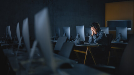 Fototapete - Stressed Male Student Sitting Alone in College Informatics Room, Working Late Evenings on Computer Science Project. Tired Scholar Study IT on Computer in University, Writing Homework.
