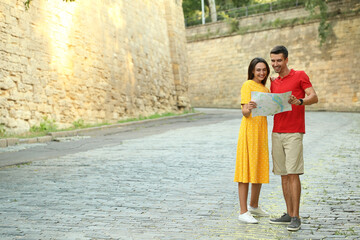 Wall Mural - Couple of young tourists with map on city street