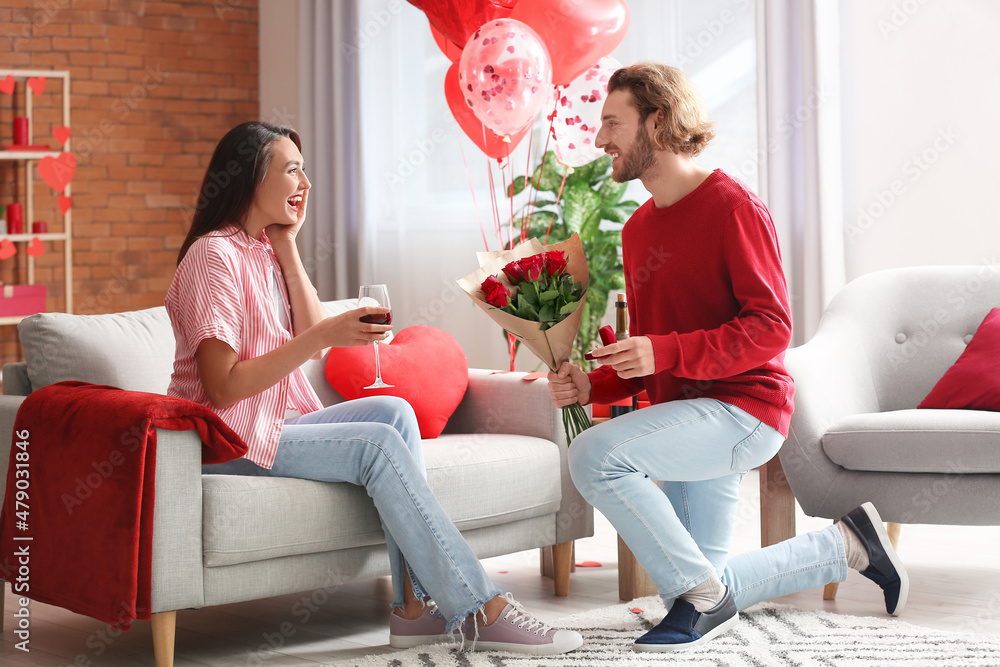 Young man proposing to his girlfriend at home on Valentine's Day