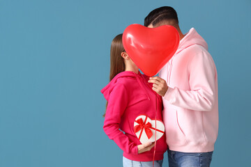 Poster - Happy young couple with gift and balloon on color background. Valentine's Day celebration