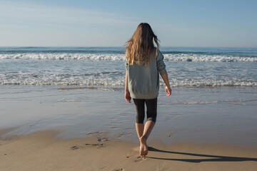 Wall Mural - Beautiful young girl walking quietly on the sunny beach