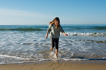 Wall Mural - pretty girl full of vitality running and jumping on the sunny beach