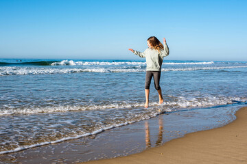 Wall Mural - pretty girl full of vitality running and jumping on the sunny beach