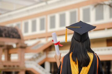 Graduates raise their hands to celebrate graduation with diplomas and pride and happiness.