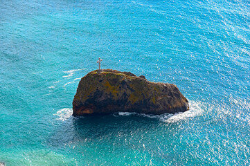 rock with a christian cross in the sea