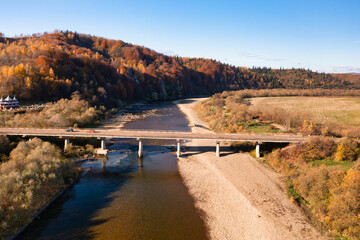 Road bridge over narrow river leading to terracotta forest