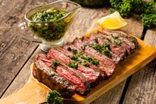 Juicy Slices Of Chopped Beef Steak With Aromatic Chimichuri Sauce On A Wooden Table.