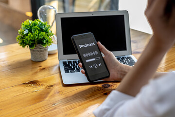 Person holding a smartphone in front of a podcast application display, using a smartphone to listen to podcasts over the Internet network. Concept of using smartphones, entertainment media and online.
