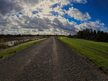 Wide Angle View Of A Levee Gravel Road On A Cloudy Day