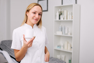 Wall Mural - Portrait of female professional beauty doctor holding product in a hand.