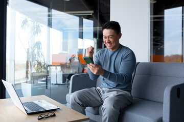 close-up photo of male businessman using phone in modern office, asian looking at phone display and 