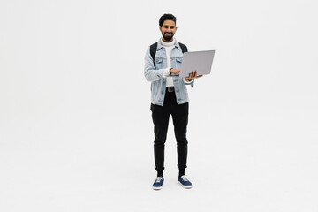 Indian handsome young student using laptop and carrying backpack isolated on white background