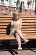 © alexmak - Girl laughing while sitting on bench in the park. happy childhood