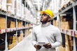 © Art_Photo - Portrait of smiling african american engineer man order details on tablet checking goods and supplies on shelves with goods background in warehouse.logistic and business export