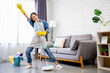 © PBXStudio - Happy young Asian woman cleaning her home, singing at mop like at microphone and having fun, free space.