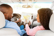 © Prostock-studio - Happy black couple looking at map sitting inside car