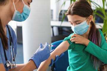 Wall Mural - Schoolgirl Receiving Coronavirus Vaccine Injection Sitting With Doctor Indoor