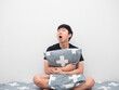 © Thanasak - Asian man sit on the bed hug pillow feeling sleepy and yawn