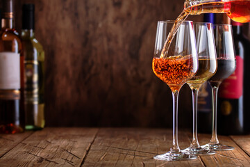 Wall Mural - Red, white and rose wine in glasses on wooden background and collection of wine bottles, copy space