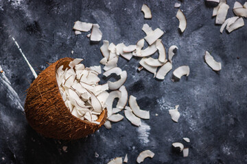 Wall Mural - healthy snack: home made roasted coconuts chips in coconut bowl on dark background. Vegan. Clean eating. Plant based.