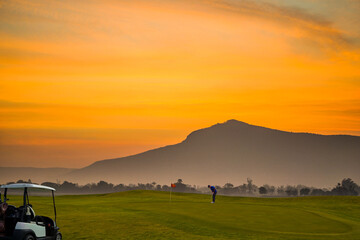 Wall Mural - Silhouette Professional golfer playing golf at golf course ,golf cart and sun sky background.