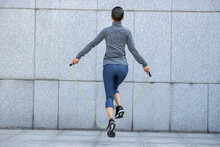 Fitness Woman Rope Skipping Against City Wall
