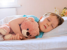 A Little Boy Sleeps With A Toy Bear In His Hands