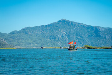 Tourist pleasure boat on the Dalyan River, next to the rocks, which contain the Lycian tombs, in Mugla Province located between the districts of Marmaris and Fethiye on the south-west coast of Turkey