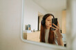© Irina_Evva - Teenage girl in headphones in front of mirror takes selfie