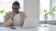 © stockbakers - African Man Coughing while using Laptop in Office