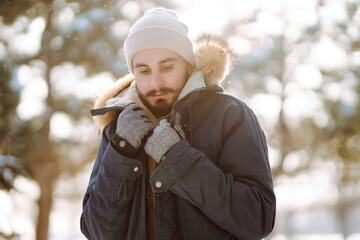 Wall Mural - Handsome bearded young  man standing outdoors fur hood in winter season forest. Season holiday leisure. Nature.