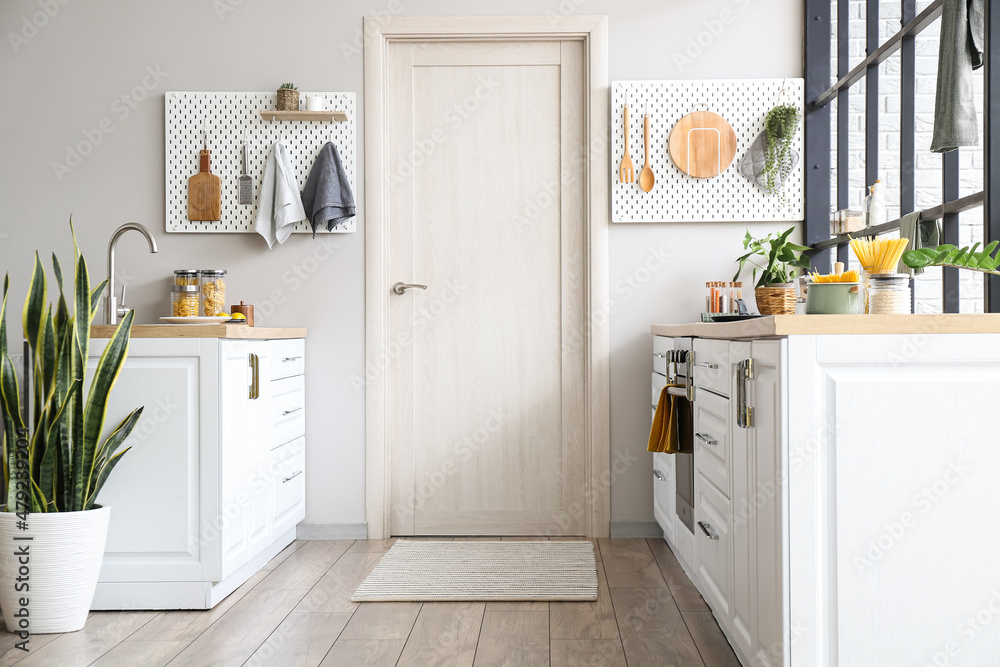 Interior of modern kitchen with white counters, door and peg boards ...