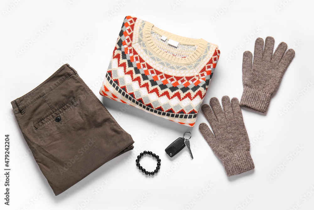 Male sweater, pants, gloves and car key on white background