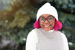 Portrait of happy positive cheerful teen teenager girl with dyed hair pink hairstyle, young cute black African Afro American woman is smiling in glasses and hat outdoors in park, looking at camera