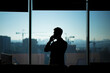 © Liubomir - Silhouette of a businessman man in a modern office on the background of the window, a man talking on the phone