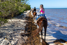 Young Woman Looks Back On Horseback Ride On Tropical Island Beach Of Mexico