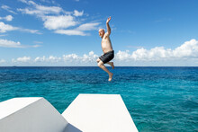 Adult Man Jumping Into Colorful Blue Caribbean Sea Off Diving Platform On The Tropical Island Of Cozumel In Mexico