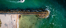 Panoramic Drone Shot Of Beach And Ocean With Seawall And Fishing Boat

