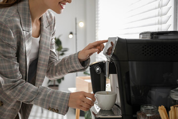 Canvas Print - Young woman preparing fresh aromatic coffee with modern machine in office, closeup