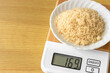 デジタルキッチンスケールで茶色い砂糖（粗糖）を量るイメージ