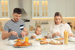 © New Africa - Happy family having breakfast together at table in kitchen