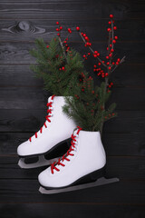 Canvas Print - Pair of ice skates with Christmas decor on black wooden background, flat lay