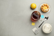 Flat Lay Composition With Tea Bag In Ceramic Cup Of Hot Water And Dessert On Grey Table. Space For Text