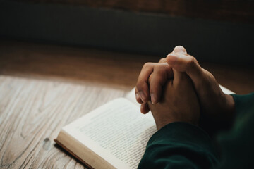 man hands clasped together on holy bible in church concept for faith, spirituality, and religion, ma